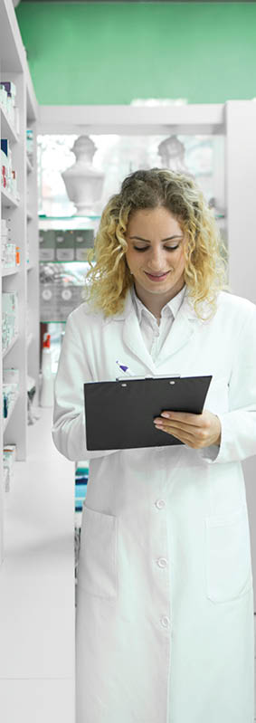 Pharmacist in white uniform walking by the shelf with medicines and checking inventory  Pharmaceutical industry 